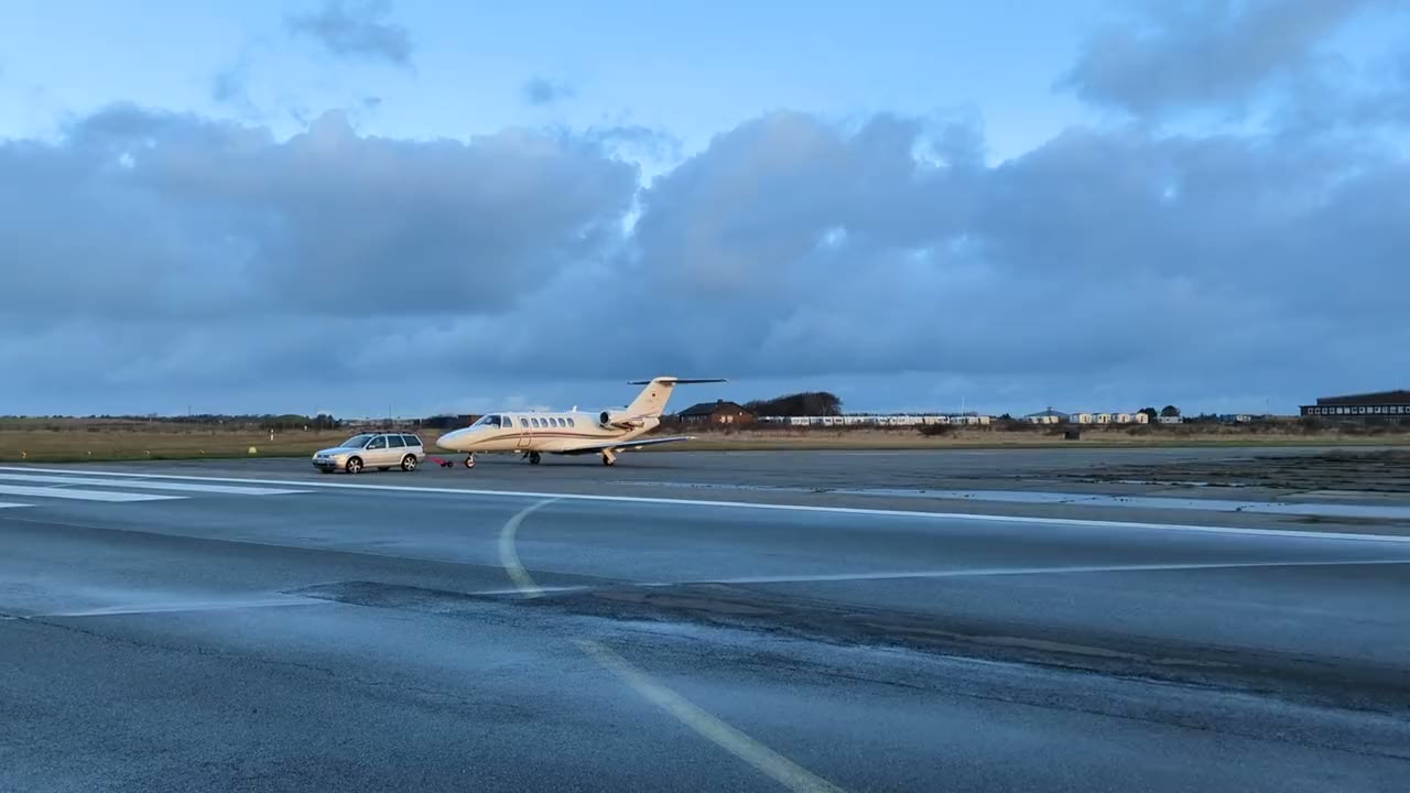 Light business jet being towed across the ramp at dusk